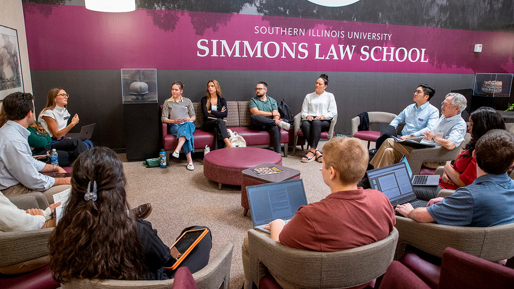 People sitting in a circle with Simmons Law School on the wall behind