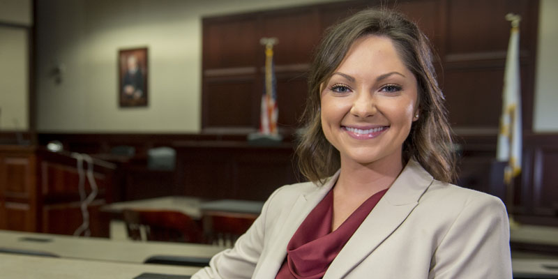 SIU student poses at a table in a courtroom